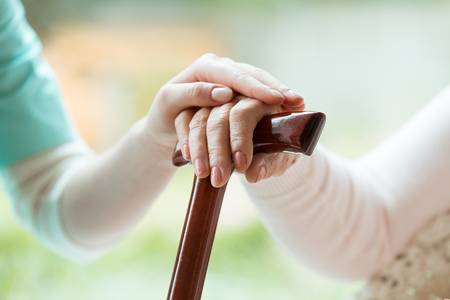 88394349-senior-holding-hands-on-walking-cane-and-nurse-supporting-her-in-nursing-home
